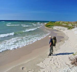 A backpacker pauses along a beach on North Manitou Island.